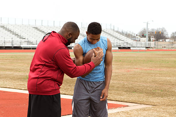 Coach providing skills position training for a wide-reciever football athlete.